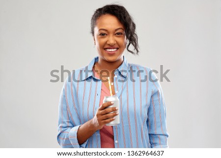 drinks and people concept - happy african american young woman drinking soda from can with paper straw over grey background