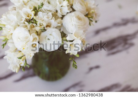 White bouquet of freesia and ranunculus on marble background