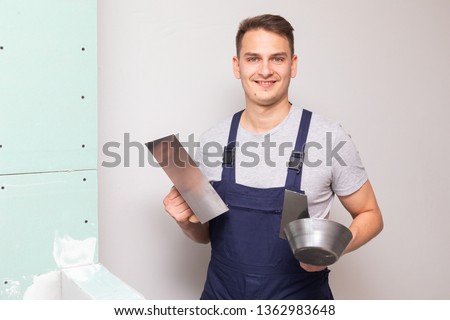 Picture of a  worker holding a spatula filling in the walls in a new apartment