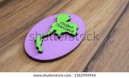 Souvenir or fridge magnet from Thailand on wooden background