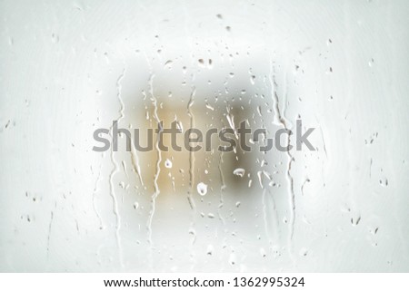 Rain drops on window with house and church in background, rainy day .