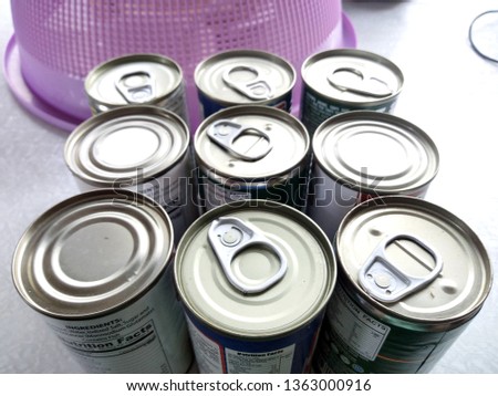 Easy open tin can tops together with non-easy open tin can tops of sardines stocked at home.
