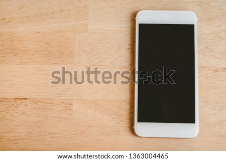 White smart phone with isolated screen on wooden desk. - Image