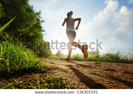Young lady running on a rural road during sunset Royalty-Free Stock Photo #136301591