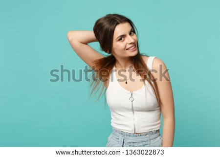 Portrait of beautiful young woman in light casual clothes looking camera, holding hair isolated on blue turquoise background in studio. People sincere emotions, lifestyle concept. Mock up copy space