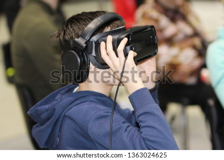 Virtual reality glasses with headphones. Goggles-helmet additional reality worn on the person. The man is in three-dimensional virtual reality.