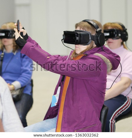 A girl takes a selfie with glasses of virtual reality. Goggles-helmet additional reality worn on a woman. The girl is in three-dimensional virtual reality.
