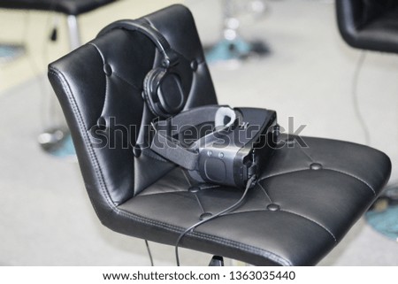 On the chair are glasses for virtual reality with headphones. Goggles-helmet additional reality. Located in the three-dimensional virtual reality.