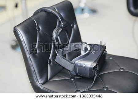 On the chair are glasses for virtual reality with headphones. Goggles-helmet additional reality. Located in the three-dimensional virtual reality.