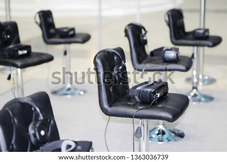On the chairs are glasses for virtual reality with headphones. Goggles-helmet additional reality. Located in the three-dimensional virtual reality.