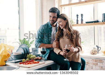 Moments of intimacy. Beautiful young couple cooking dinner and drinking wine while standing in the kitchen at home Royalty-Free Stock Photo #1363048502