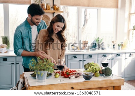 Feeling happy. Beautiful young couple cooking dinner while standing in the kitchen at home Royalty-Free Stock Photo #1363048571