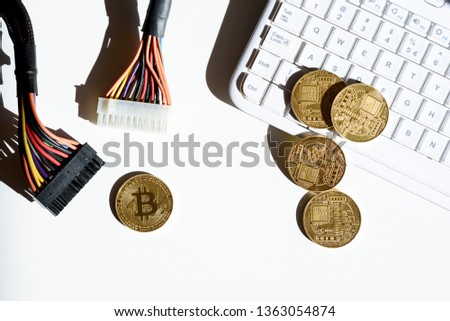Gold coins with a bitcoin symbol lying on table and white computer keyboard, next to colorful cables. Virtual crypto currency. Future of finance and payment in internet.