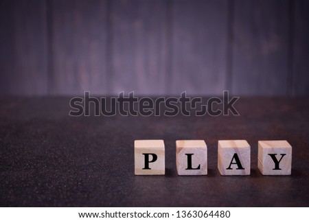 The word play on wooden cubes, on a dark background, symbols signs