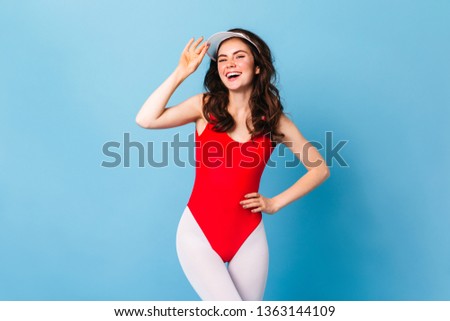 Charming athlete girl in bodysuit and white leggings in style of 80s laughs on blue background