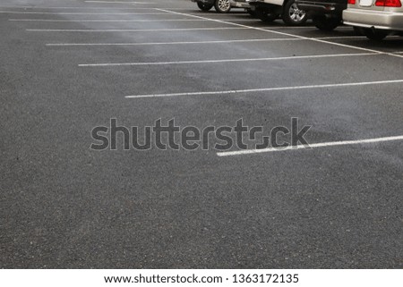 Image of empty parking spaces on asphalt ground of parking area after raining in the evening.