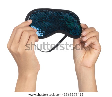 Hand holding Blue sleeping eye mask with sequins that look like fish scales isolated on white background.