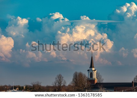 church steeple isolated in a city view with thunderstorm on horizon