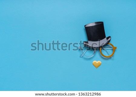 Photo booth props cylinder hat, glasses and nose of heart shape on blue background. Greeting card, text HAPPY FATHER'S DAY. Creative composition in minimal style