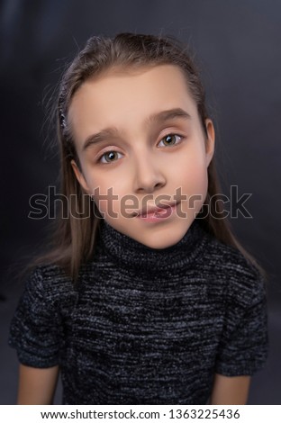Funny portrait of a cute smiling teen girl wearing a dark turtleneck. Gray background. Advertising, trendy and commercial design. Copy space. Close up.