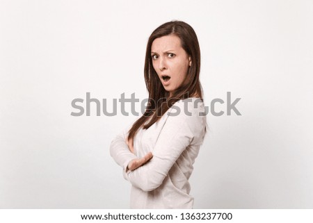 Side view of shocked irritated young woman in light clothes keeping mouth open, holding hands folded isolated on white wall background. People sincere emotions, lifestyle concept. Mock up copy space