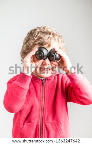 A child playing with coffee capsules using them as binoculars. Conceptual photography that tries to represent the recycling of plastic material.