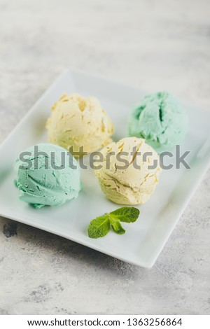 Mint and lemon ice cream with mint leaves in white plate on light concrete background