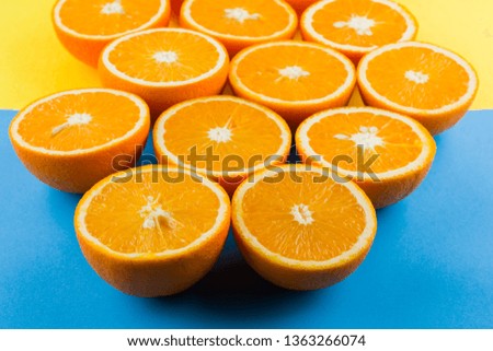 Cut halves of juicy orange on yellow blue background. Orange fruit, citrus minimal concept. Creative summer food minimalistic background. Top view, copy space