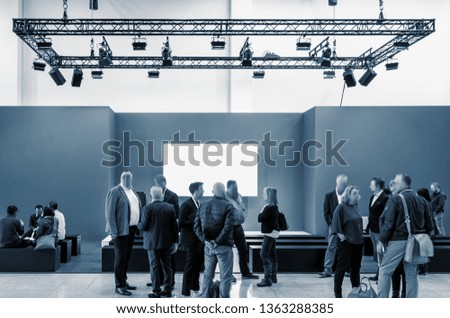 business people walking between trade show booths at a public event exhibition hall and copy space for individual text 