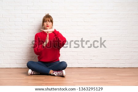 Redhead woman siting on the floor making time out gesture