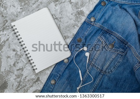 Empty spiral notebook with white page on a marble background. Spiral notepad and homemade concrete pot on a table. Sketch-book for input the text, top view. Denim on stone.