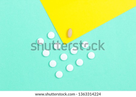Minimalistic medical concept. A group of identical white tablets and one unique tablet on a pastel colored background. Top view