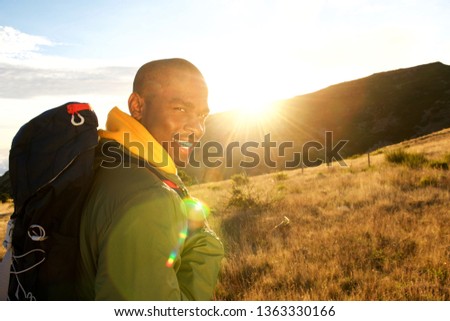 Close up side portrait of happy man hiking in mountains with backpack
