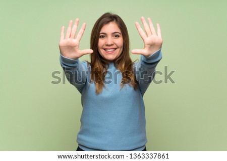 Young girl over green wall counting ten with fingers