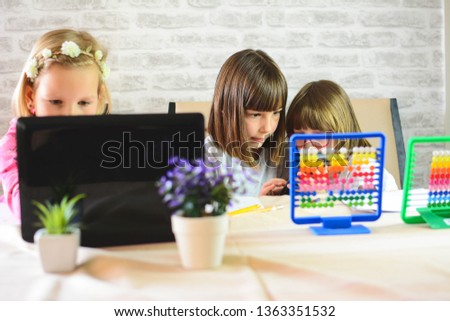 Education, elementary school, learning, technology and people concept. Schoolgirl Watching Educational Video on laptop Computer Together Inside the room. Toned picture.