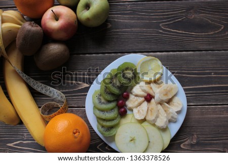 Bananas, kiwi, apples are  the on a wooden table. 