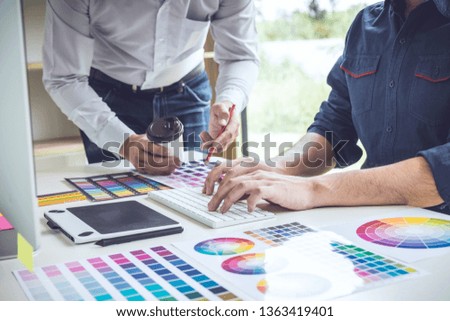 Two colleagues creative graphic designer working on color selection and drawing on graphics tablet at workplace.