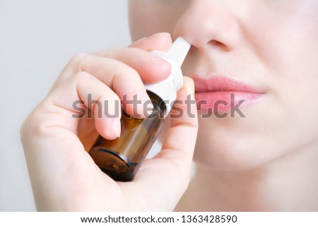 Nasal spray.  Beautiful young woman. Closeup. Face with nasal drops. Close-up of female spraying medical nasal spray in her nose. Cold and flu, health care concept. 