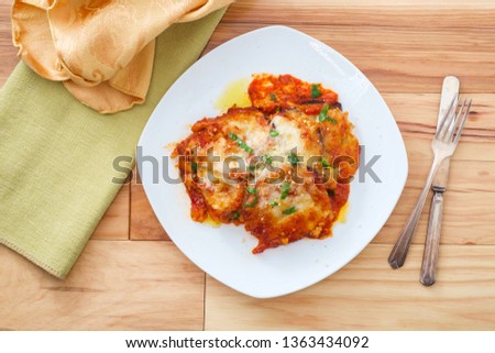 Home made Italian baked Eggplant parmesan on wooden kitchen table Royalty-Free Stock Photo #1363434092