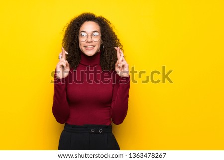 Dominican woman with turtleneck sweater with fingers crossing and wishing the best