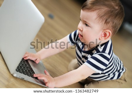 Little hands on keyboard. Little baby boy is watching cartoons on laptop.