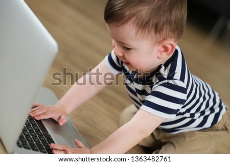 Little hands on keyboard. Little baby boy is watching cartoons on laptop.