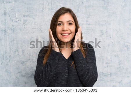 Young girl over grunge wall with surprise facial expression