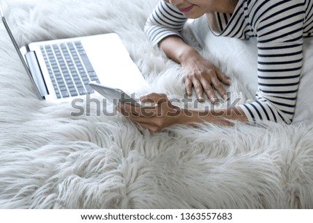 girl lying on the bed play her smartphone and laptop computer