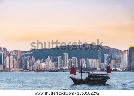 Traditional sailing ship with Hong Kong modern commercial building background during sunset, viewed from victoria harbor, Hong Kong