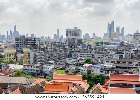 Amazing Bangkok skyline, Thailand. Scenic view of old residential buildings and water towers in Pom Prap Sattru Phai district. Skyscrapers are visible on cloudy sky background. Beautiful cityscape. Royalty-Free Stock Photo #1363591421