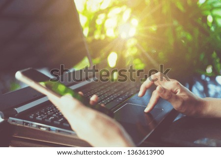 Woman hand using laptop and smartphone to work study with cafe shop colorful beautiful bokh background. Business, financial, trade stock maket and social network concept.