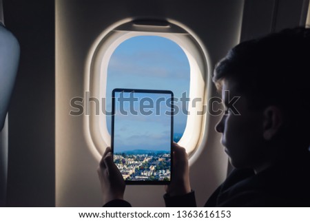 Caucasian boy using tablet pc taking picture through airplane window San Francisco cityscape. California. USA