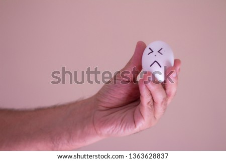 A man holding an egg with a funny face. Conceptual image Cartoon painted by hand on an egg.
