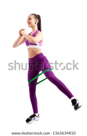 Sporty woman does  exercises on legs, makes lunges  with sport fitness rubber bands  on white background. Photo of muscular woman in sportswear on white background. Strength and motivation. 